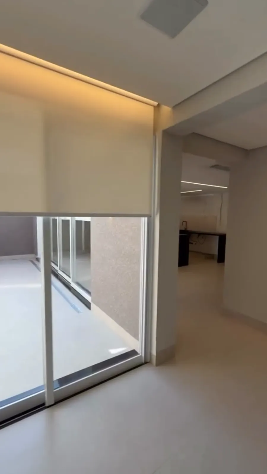 Sala com rolô screen cobrindo a porta de vidro