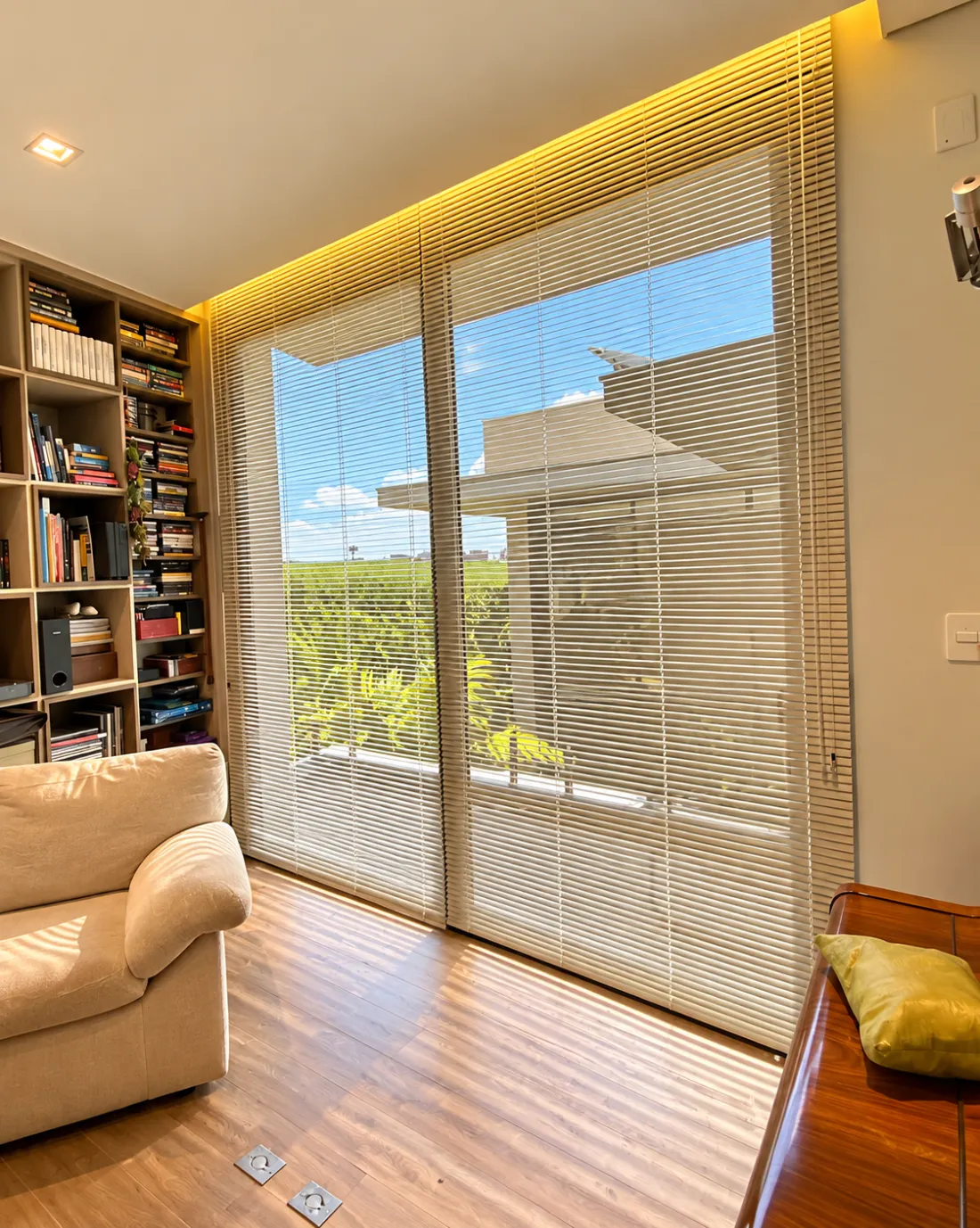 Sala com estante de livros e persiana horizontal de lâminas claras